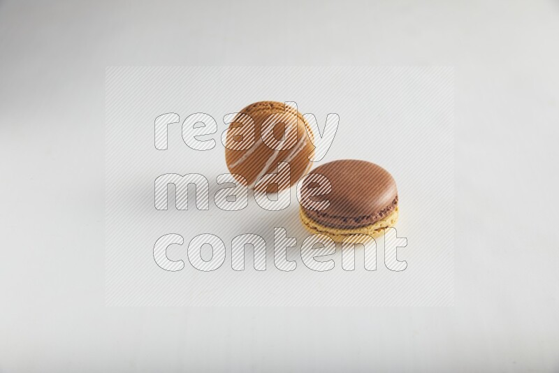 45º Shot of of two assorted Brown Irish Cream, and Yellow, and Brown Chai Latte macarons on white background