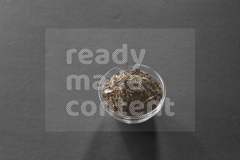 A glass bowl full of basil on black flooring