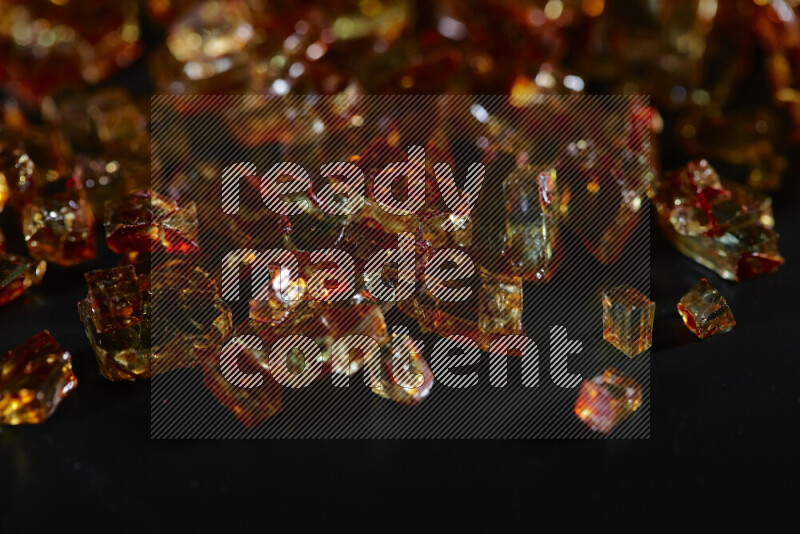 Transparent orange fragments of glass scattered on a black background