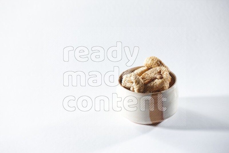 A beige ceramic bowl full of dried figs on a white background in different angles