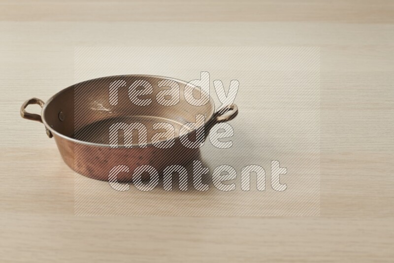 A small copper pan on light wooden background