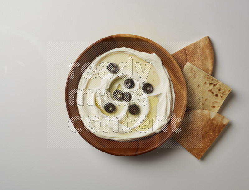 Lebnah garnished with sliced olives in a wooden plate on a white background