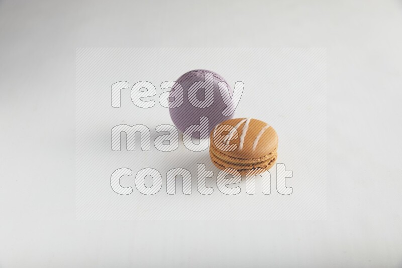 45º Shot of of two assorted Brown Irish Cream, and Purple Blueberry macarons on white background