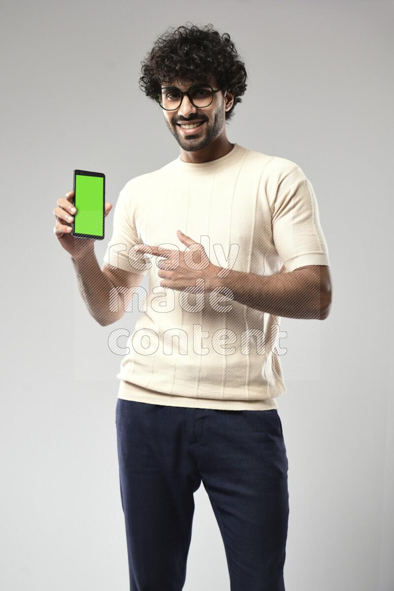 A man wearing casual standing and showing a phone screen on white background
