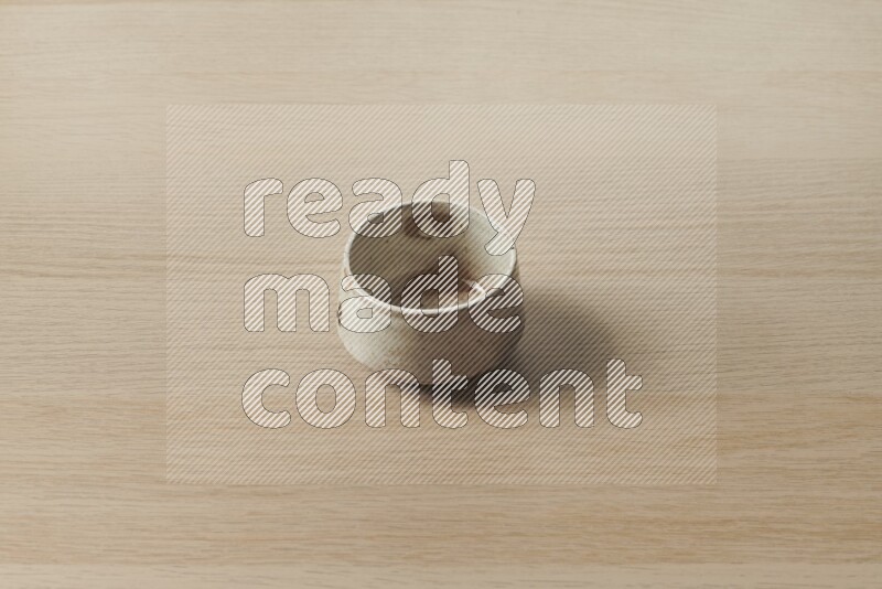 A beige pottery bowl on light wooden background