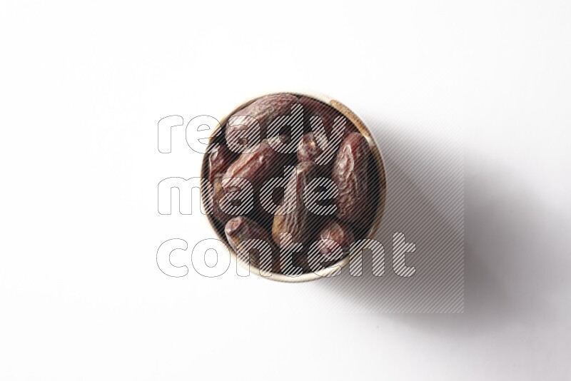 Dates in a beige pottery bowl on white background