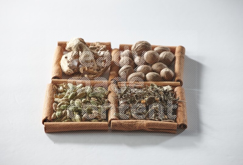 4 squares of cinnamon sticks full of nutmegs, dried ginger, cardamom and dried basil on white flooring