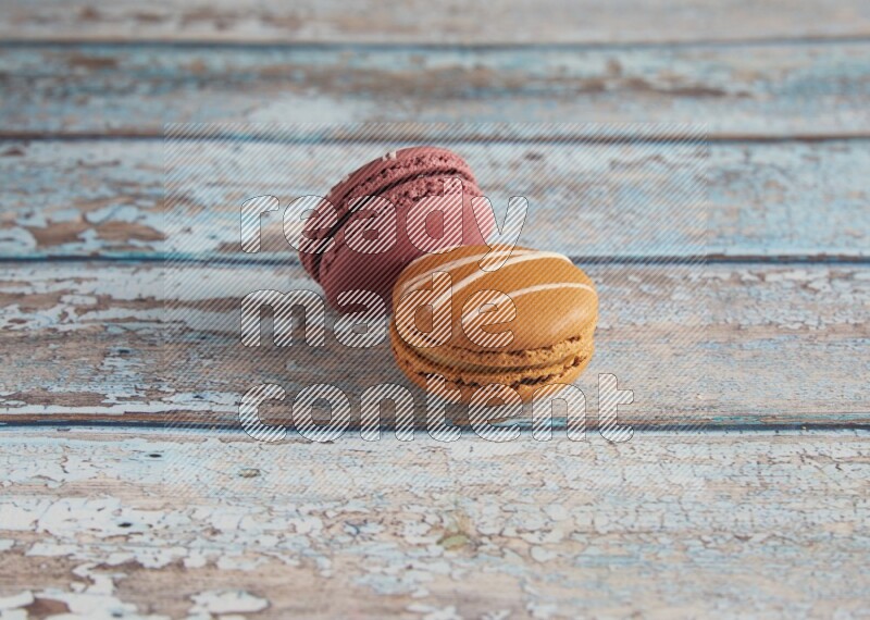 45º Shot of of two assorted Brown Irish Cream, and Red Poppy Flower macarons  on light blue background