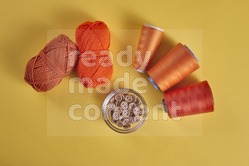 An orange collection of sewing and tailoring tools arranged on a yellow background