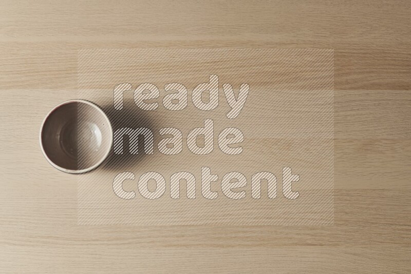 A multicolored pottery bowl on light wooden background