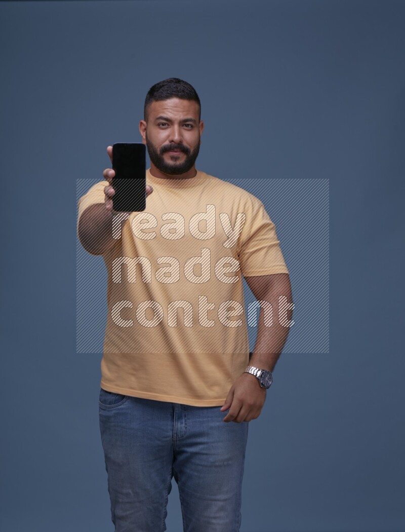 A man Showing His Smart Phone on Blue Background wearing Orange T-shirt
