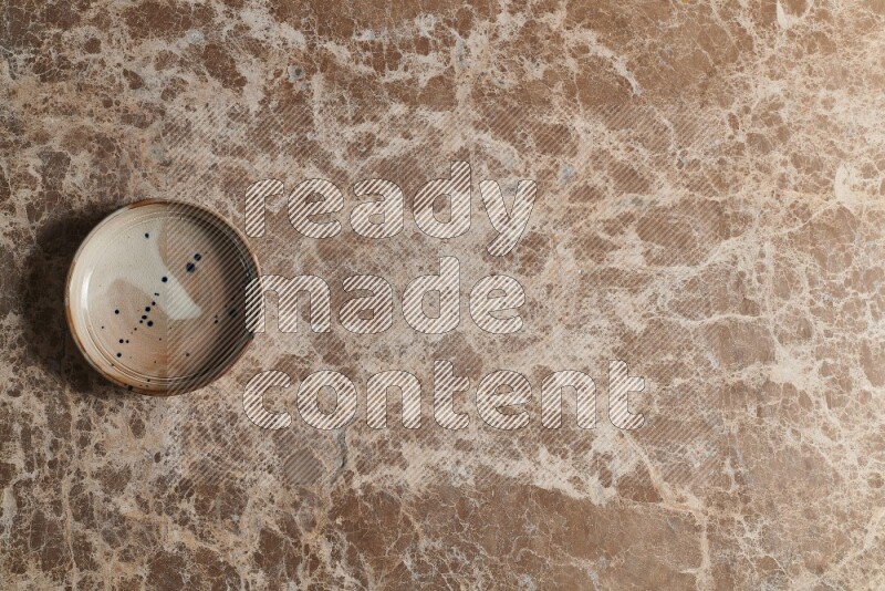 A multicolored pottery bowl on beige marble background