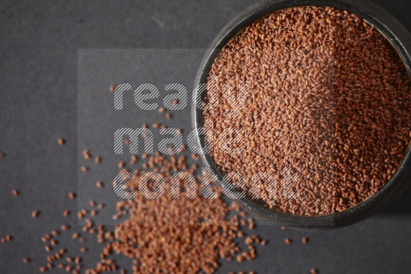 وعاء فخاري أسود ممتلئ ببذور حب الرشاد على أرضية سوداء