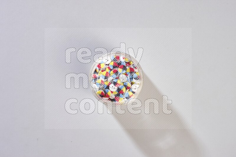 Colored buttons in a glass jar on grey background