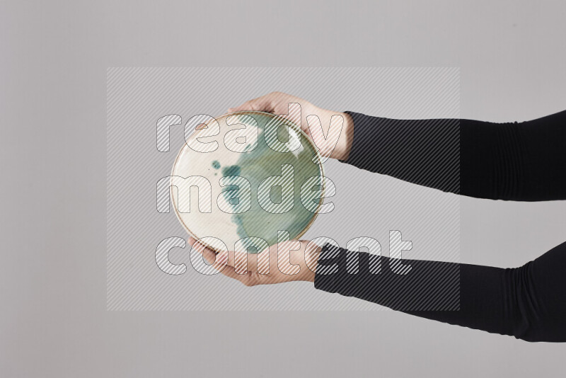 A woman in black abaya holding different pottery essentials in different positions