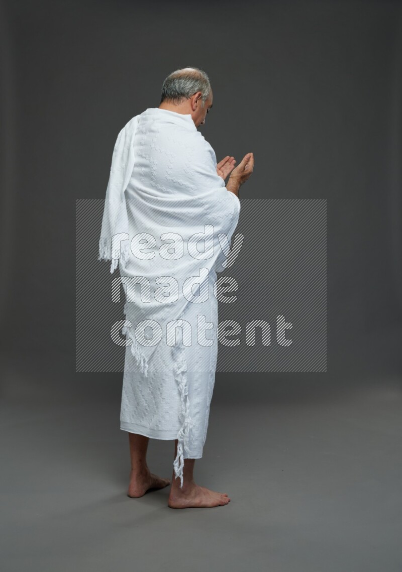 A man wearing Ehram Standing dua'a on gray background