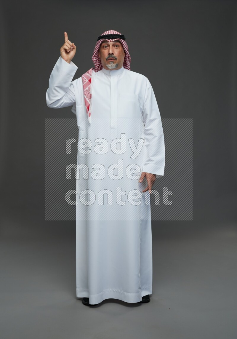Saudi man with shomag Standing Interacting with the camera on gray background