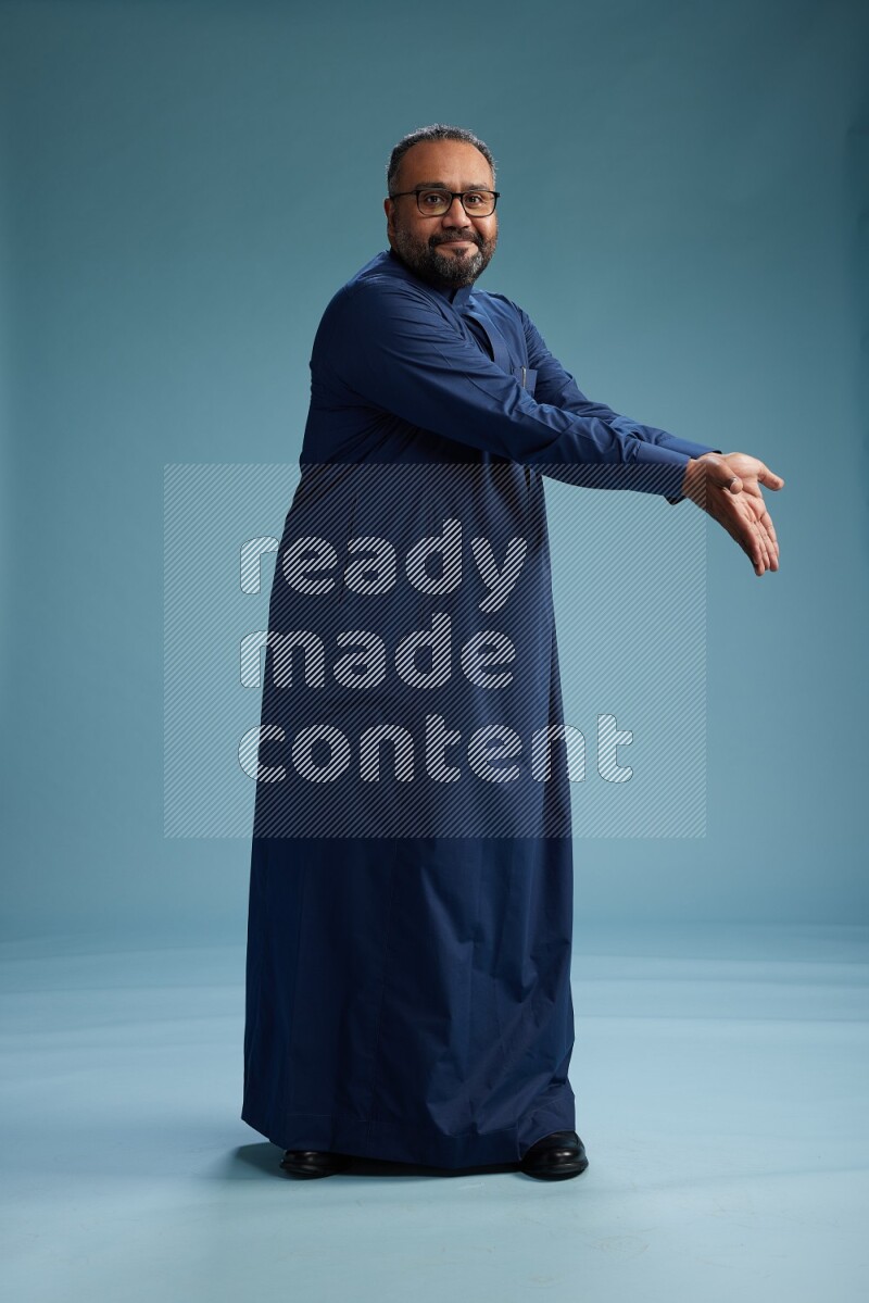Saudi Man without shimag Standing Interacting with the camera on blue background