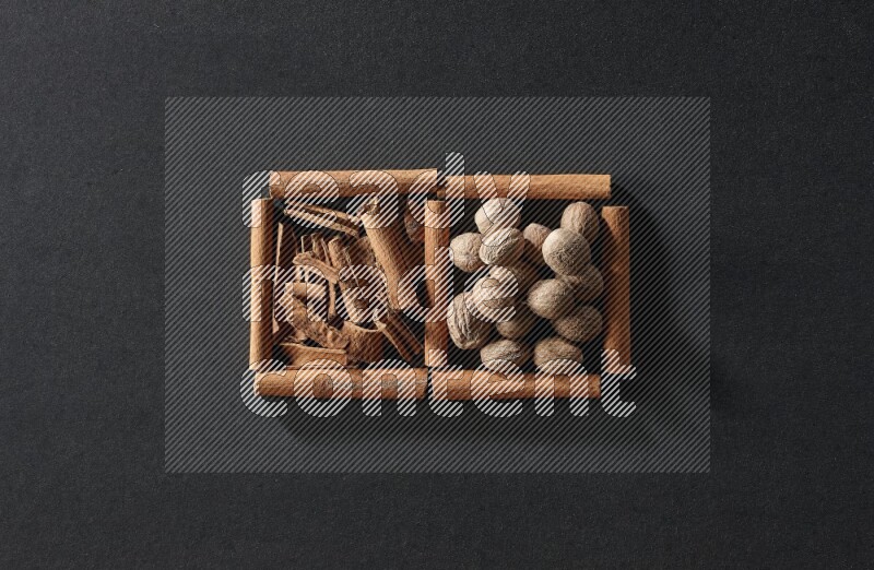 2 squares of cinnamon sticks full of cinnamon and nutmeg on black flooring