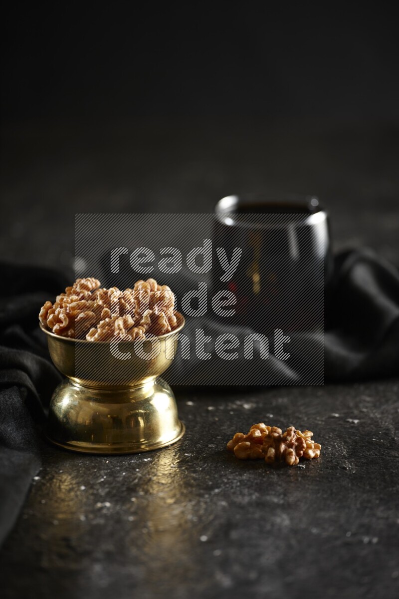 Nuts in a metal bowl with tamarind and a napkin in a dark setup
