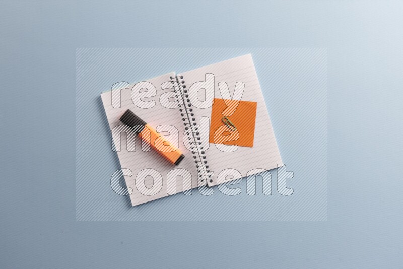 A blank open notebook with different school supplies on blue background