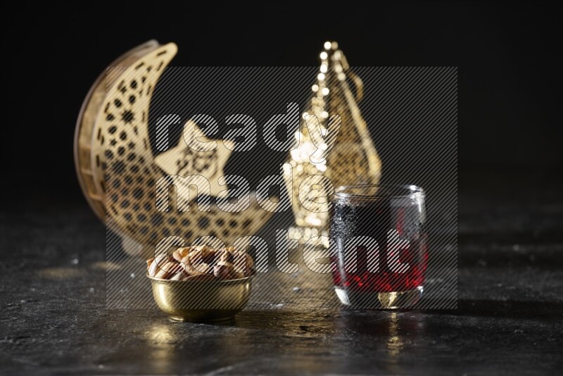Nuts in a metal bowl with Hibiscus beside golden lanterns in a dark setup