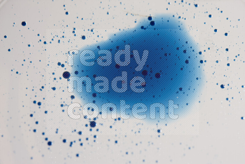 لقطات مقربة لقطرات ألوان مائية زرقاء على سطح الزيت على خلفية بيضاء