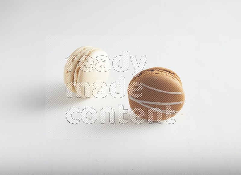 45º Shot of of two assorted Brown Irish Cream, and White Caramel fleur de sel macarons on white background