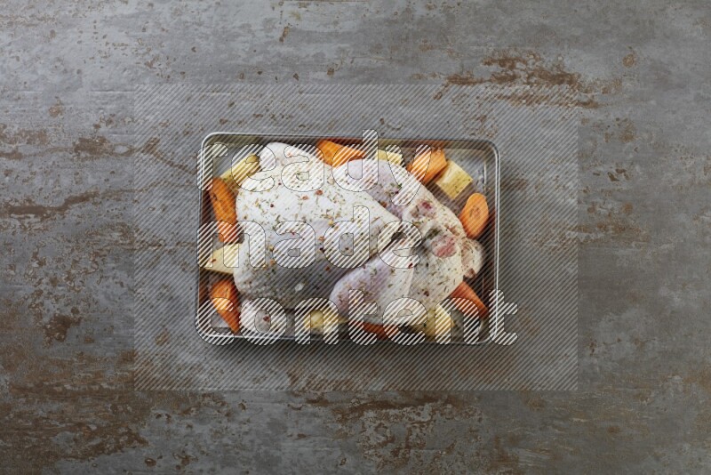 whole Raw chicken on a small oven trey direct on a rustic grey background