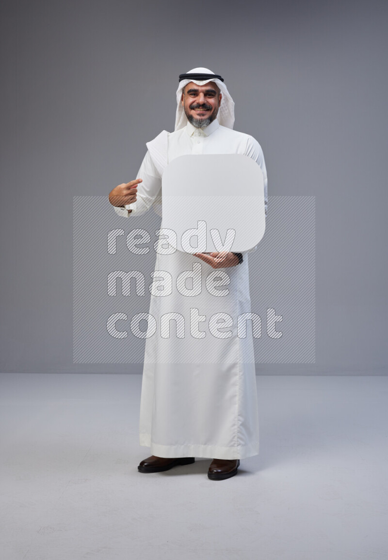 Saudi man Wearing Thob and white Shomag standing holding social media sign on Gray background