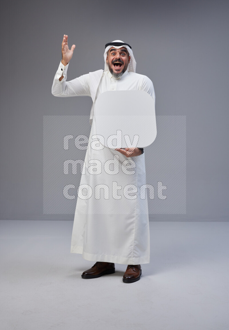 Saudi man Wearing Thob and white Shomag standing holding social media sign on Gray background