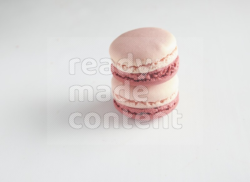 45º Shot of two Pink Litchi Raspberry macarons on white background