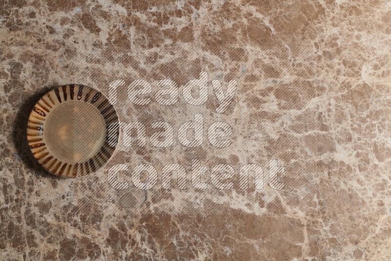 A multicolored pottery plate on beige marble background