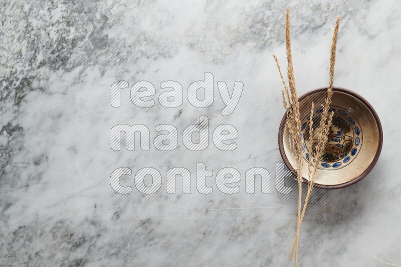 Wheat stalks on decorative pottery plate on grey marble background