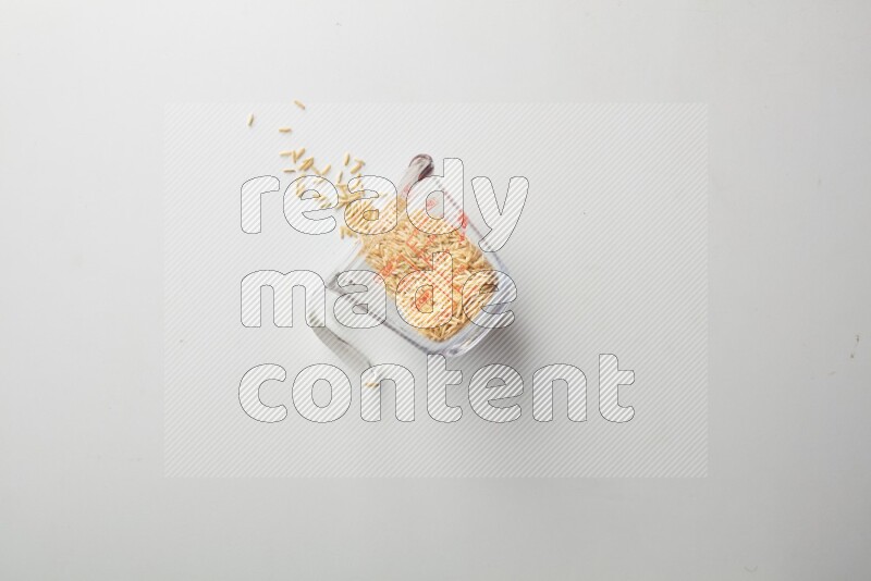 Top-view shot of long grain brown rice in a container on white background