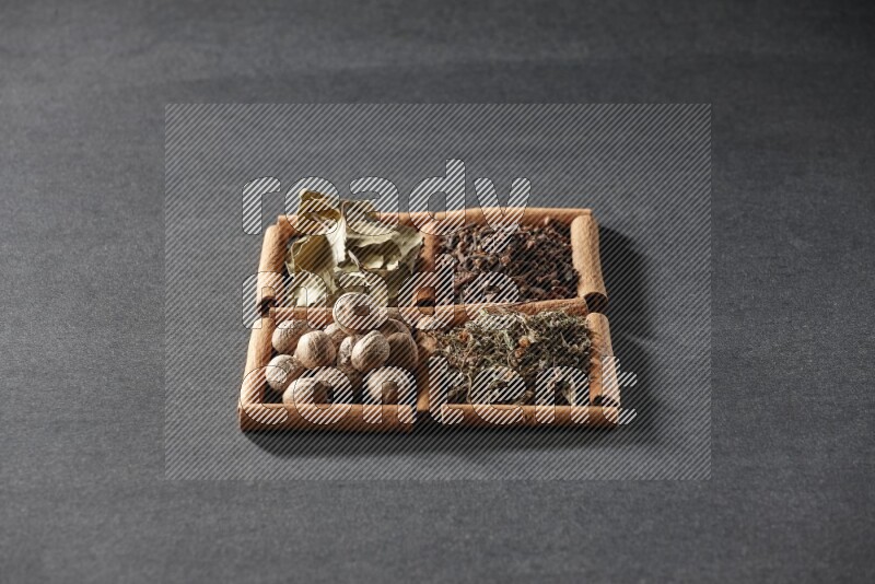 4 squares of cinnamon sticks full of bay laurel leaves, dried basil, cloves and nutmegs on black flooring