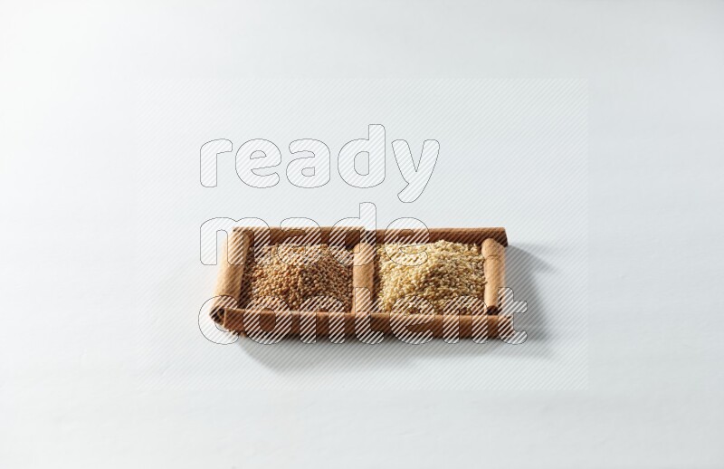 مربعان من أعواد القرفة ممتلئان بحبوب الخردل وبذور السمسم علي خلفية بيضاء