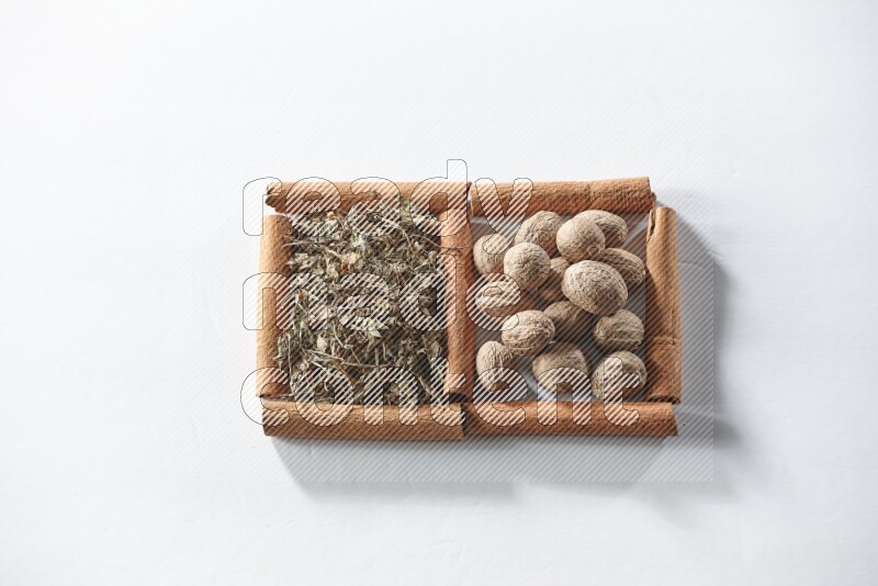 2 squares of cinnamon sticks full of dried basil and nutmegs on white flooring