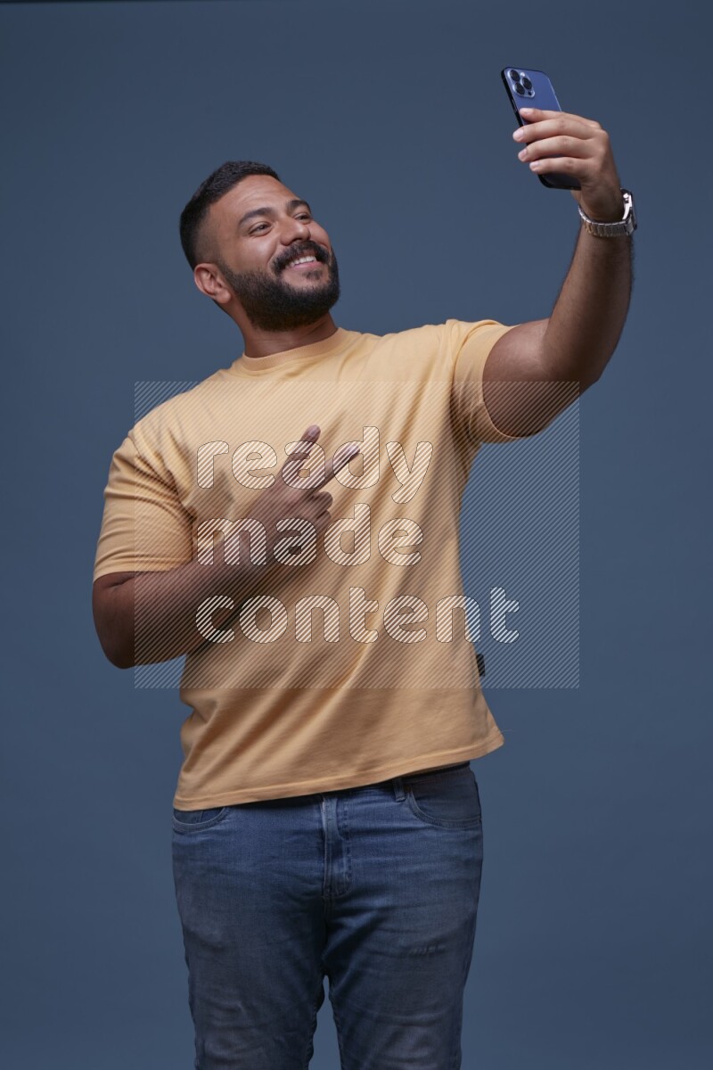 A man Taking A Selfie on Blue Background wearing Orange T-shirt