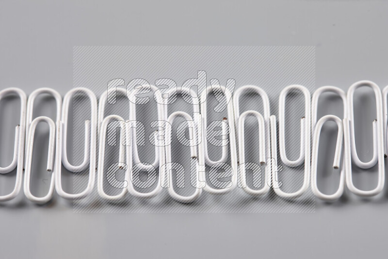 White paper clips isolated on a grey background