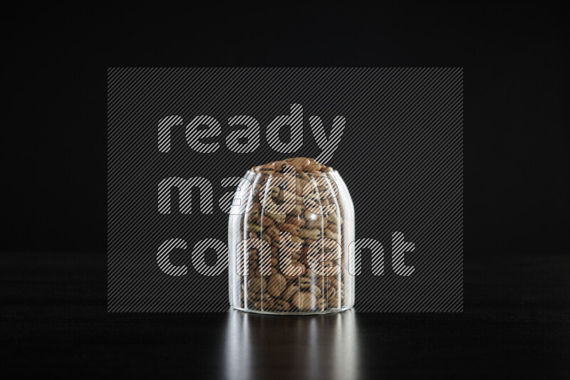 Fava beans in a glass jar on black background