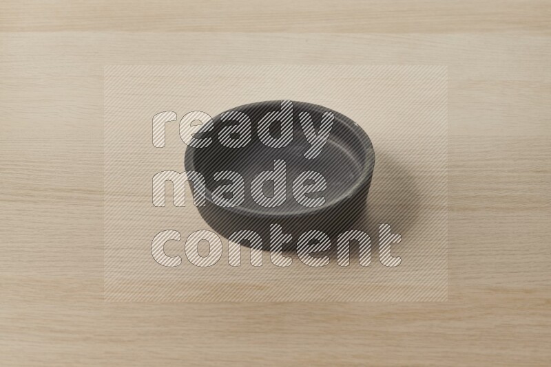 A black pottery bowl on light wooden background