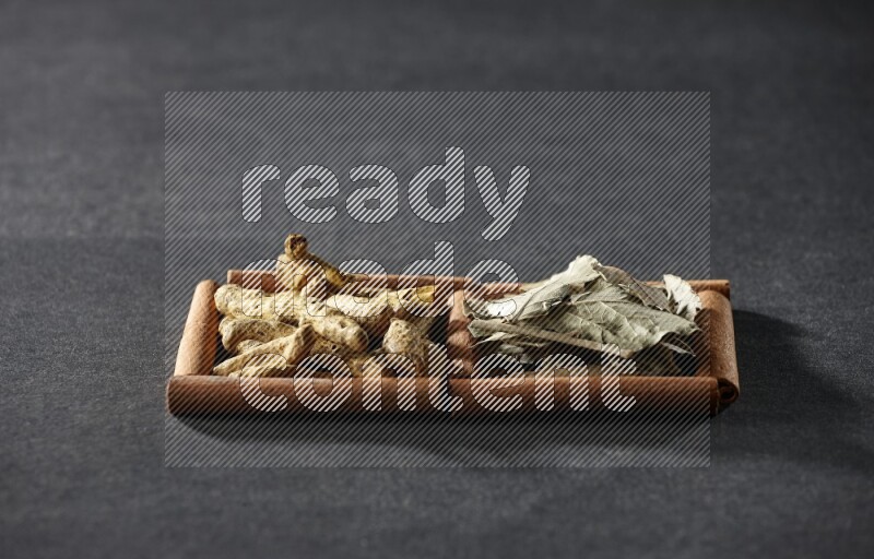 2 squares of cinnamon sticks full of bay laurel leaves and turmeric fingers on black flooring