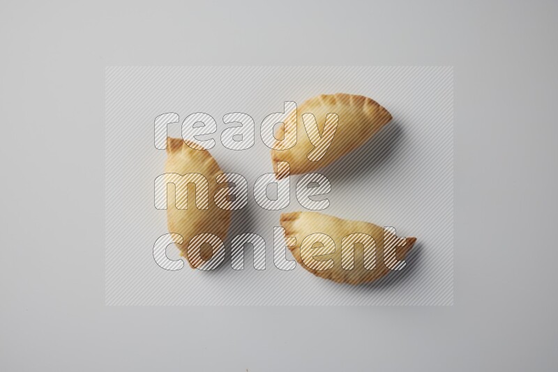 Three fried sambosa from a top angle on a white background