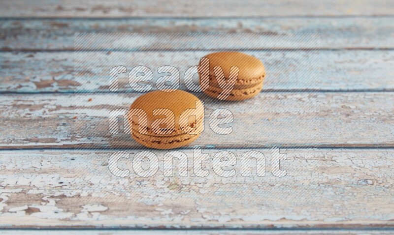 45º Shot of two Brown Maple Taffy macarons on light blue wooden background