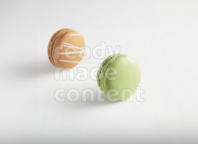 45º Shot of of two assorted Brown Irish Cream, and Green Pistachio macarons on white background