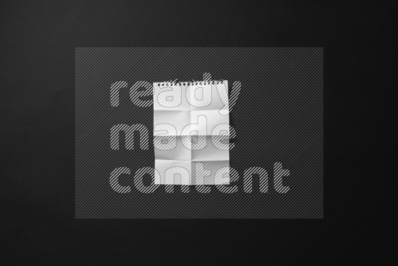 Folded notebook sheet on black background