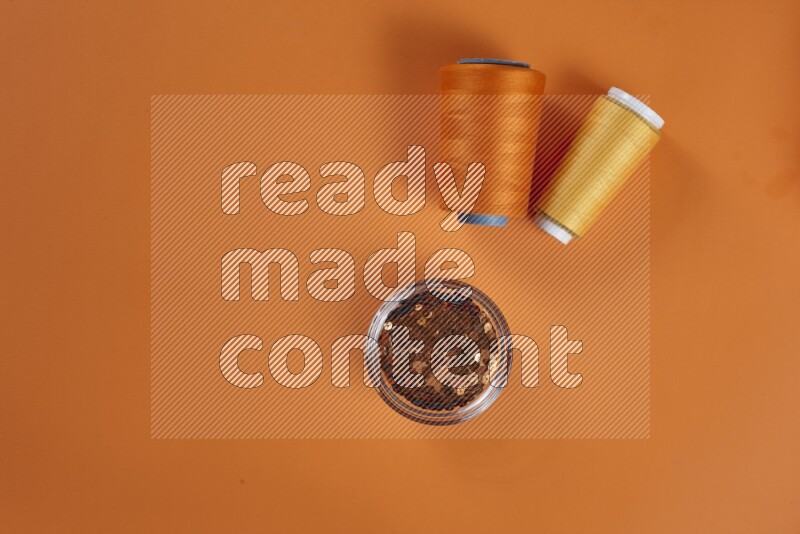 A yellow collection of sewing and tailoring tools arranged on a orange background