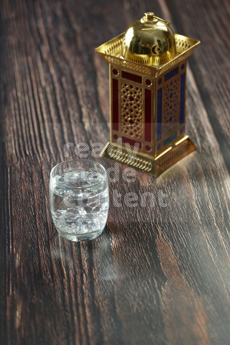 A golden lantern with different drinks, dates, nuts, prayer beads and quran on brown wooden background