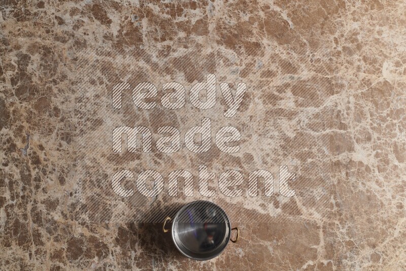 A small copper pot on beige marble background